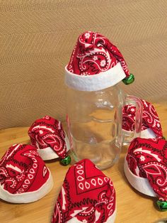 red bandana hats are sitting next to a glass mug and coasters on a wooden table