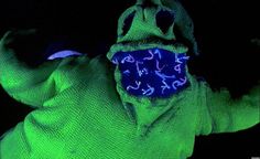 a person wearing a green costume with blue writing on it's face and hands