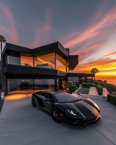 a black sports car is parked in front of a modern house with sunset behind it