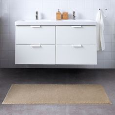 a white bathroom with two sinks and a rug