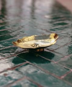 a metal bowl sitting on top of a tiled floor