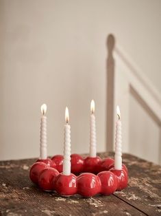 four candles are arranged in the shape of a heart on a table with red apples