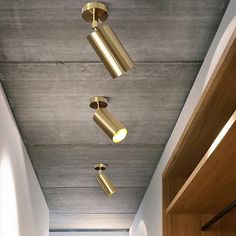 three lights are hanging from the ceiling in an office hallway with wood paneling and white walls