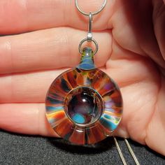 a person holding a glass pendant in their hand