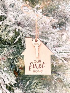 a wooden ornament hanging from a christmas tree with the words our first home on it