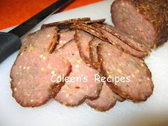 sliced meat sitting on top of a white cutting board next to a pair of scissors