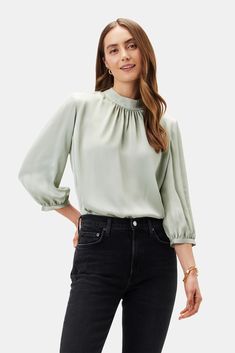 Sophisticated yet casually cool, our mock neck blouse gives just a hint of romance. Its elegant shirring and soft puff sleeves make it the ultimate day-to-night top. Mock neck, 3/4 puff sleeve blouse with shirring detail Keyhole slit with fabric-covered button at back of neck 100% Recycled Polyester 24" in length Ethic Green Blouse Outfit, Aesthetic Loungewear, Mint Green Blouses, Mom Wardrobe, Night Tops, Cotton Long Dress, Mock Neck Blouse, Puff Sleeve Blouse, Fabric Covered Button