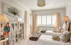 two beds in a room with white walls and curtains on the windowsills are decorated with decorative pillows