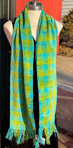 a green and blue scarf on a mannequin's dummy next to a red wall