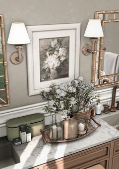 a bathroom sink with flowers and candles on the counter next to two framed pictures above it