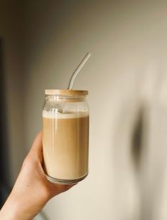 a person holding a glass jar with liquid in it and a straw sticking out of the top