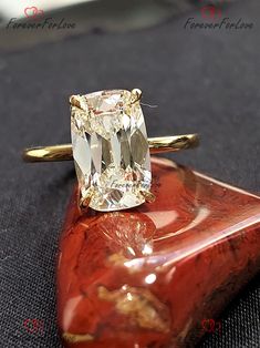 a yellow diamond ring sitting on top of a piece of red coral with gold accents