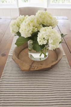 white flowers in a glass vase on a wooden tray