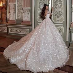 a woman in a wedding dress is standing on the floor with her arms behind her back