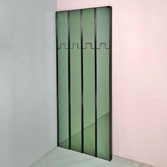 an empty room with a green door and pink wall in the corner that is partially closed