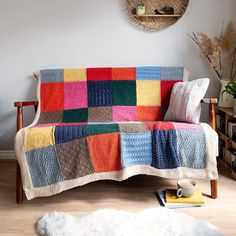 a multicolored crocheted blanket on a couch in a living room next to a rug