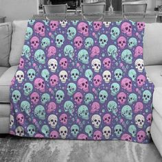 a living room with a couch covered in a purple and blue skull print throw blanket