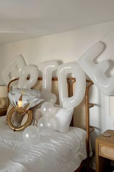 the balloons are shaped like letters and numbers on top of a bed with white sheets