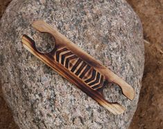 a piece of wood sitting on top of a rock next to a knife holder with zebra print