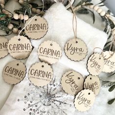 six wooden tags with the names of different countries hanging on a white towel next to greenery