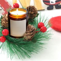 a lit candle sitting on top of a pine cone next to some cones and berries