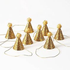 gold party hats with pom poms on them are lined up against a white background