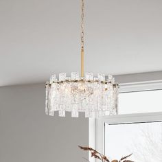 a chandelier hanging from the ceiling in a living room with a window behind it