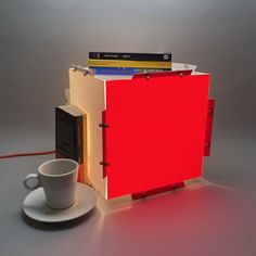 a cup and saucer are sitting next to a red box with books on it