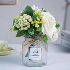 a glass jar filled with white flowers and greenery