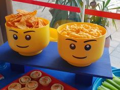 two yellow bowls filled with food sitting on top of a blue table next to other plates