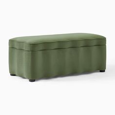 an upholstered bench in green fabric with black legs and foot rests on the ground