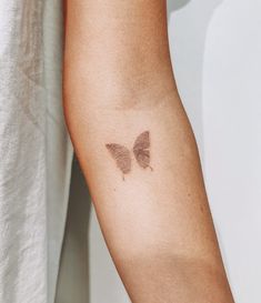 a woman's arm with a butterfly tattoo on the left side of her arm