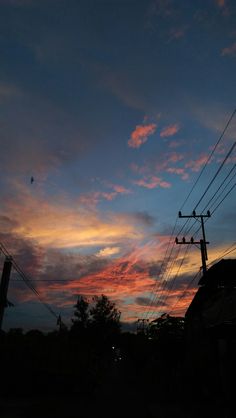 the sun is setting behind power lines and telephone poles