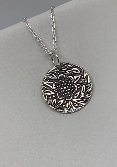 This beautiful floral circle silver necklace pendant has been entirely handmade using .999 fine silver. It has been cut from fine silver precious metal clay, textured, fired and oxidized. The pendant hangs from a sterling silver diamond cut cable chain. This unique and handmade necklace features an embossed floral leaf branch pattern. Pendant size: approximately 1/2 x 1/2 inches Chain length: adjustable at 16 and 18 inches can also be customized to whatever length needed The necklace is sent in Etched Sterling Silver Round Disc Jewelry, Etched Sterling Silver Necklaces, Unique Silver Etched Necklaces, Silver Etched Sterling Silver Necklace, Silver Etched Necklace With Flower Pendant, Etched Sterling Silver Pendant Necklace, Artisan Silver Etched Necklace, Silver Etched Nature-inspired Necklaces, Sterling Silver Etched Round Disc Necklace