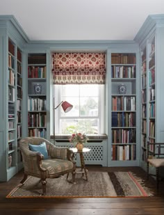 a living room filled with lots of bookshelves next to a window covered in curtains