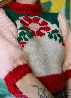 a close up of a doll wearing a sweater with flowers on it's sleeves