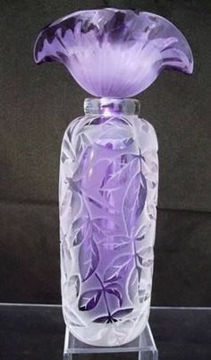 a purple glass vase sitting on top of a black table next to a dark background