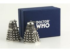 two silver thimbles sitting in front of a blue box with the doctor who logo on it