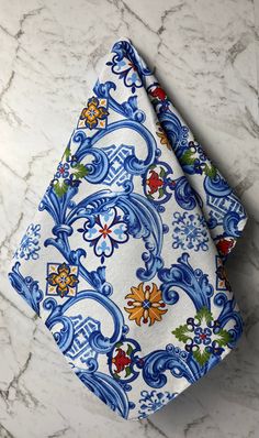 a blue and white floral print pocket square on a marble countertop with an orange flower in the center