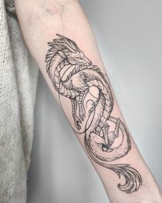 a black and white photo of a dragon tattoo on the left arm with an arrow in it