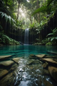 a waterfall in the middle of a pool surrounded by lush green trees and rocks with water running down it's sides