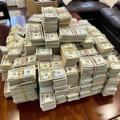 a pile of money sitting on top of a wooden table next to a black couch