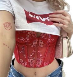 a woman wearing a red corset with tattoos on her stomach