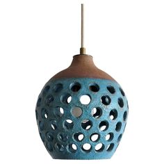 a blue and brown ceramic light fixture with holes in the center, on a white background