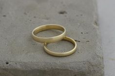 two gold rings sitting on top of a cement block