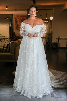 a woman in a white wedding dress posing for the camera with her hands on her hips