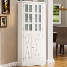 a tall white cabinet with glass doors in a living room next to a dining room table