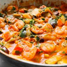 a pan filled with shrimp and vegetables on top of a stove