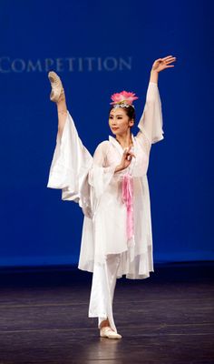 a woman in white is dancing on stage