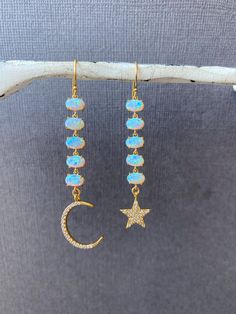 Opal Dangling Earrings, Mismatched Moon and star dangling earrings, Long gold Blue opal earrings, Bridesmaids earrings, Gift for her, jewelhavenstudio Our Opal Mismatched Moon and Star Earrings. These stunning dangling earrings feature blue opal accents, making them a perfect choice for weddings and bridesmaids. The unique design adds a touch of elegance and charm --------------------------------------------------------------------- + FEATURES + - Lab made Opal charms  - High Quality Gold plated over brass moon and star - Gold filled ear wire - Cubic Zirconia --------------------------------------------------------------------- ** HOW TO TAKE CARE OF YOUR JEWELRY ** - Remove your jewelry when swimming, sunbathing ad showering - Keep them away from chemicals like perfumes, body creams & hai Mismatched Bridesmaids Blue, Bridesmaid Blue, Blue Opal Earrings, Bridesmaids Earrings, Beads Craft Jewelry, Moon And Star Earrings, Long Gold Earrings, Moon And Star, Dangling Earrings